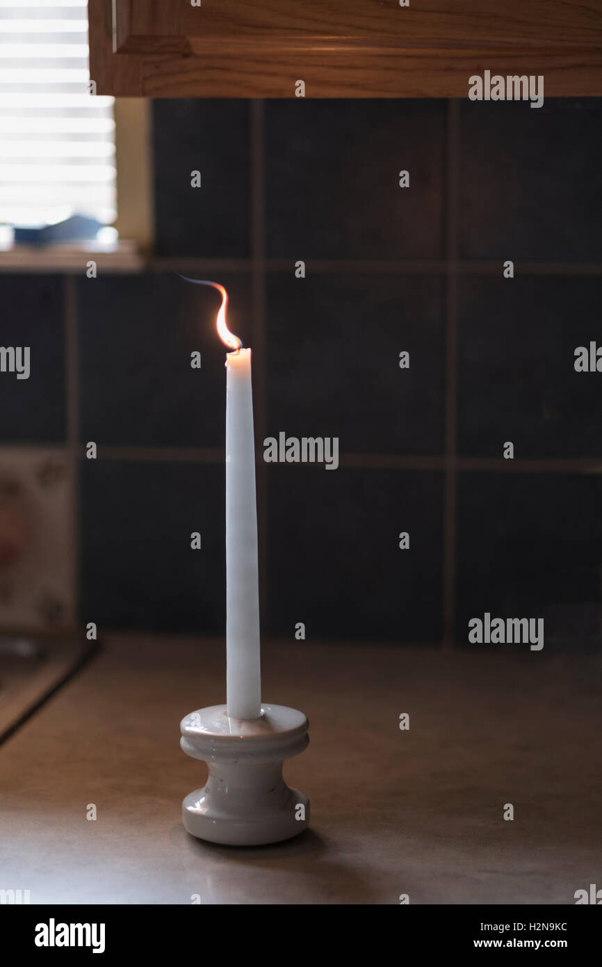 Eine weiße Kerze mit Flamme, auf eine Arbeitsplatte in der Küche. Stockfoto