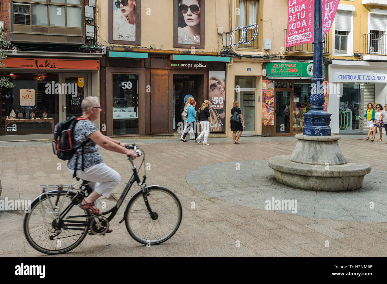 Erwachsene Frau montiert auf einem Fahrrad mit Rucksack auf dem Rücken für eine Einkaufsstraße in der Stadt Santander, Kantabrien, Spanien,-Eur Stockfoto