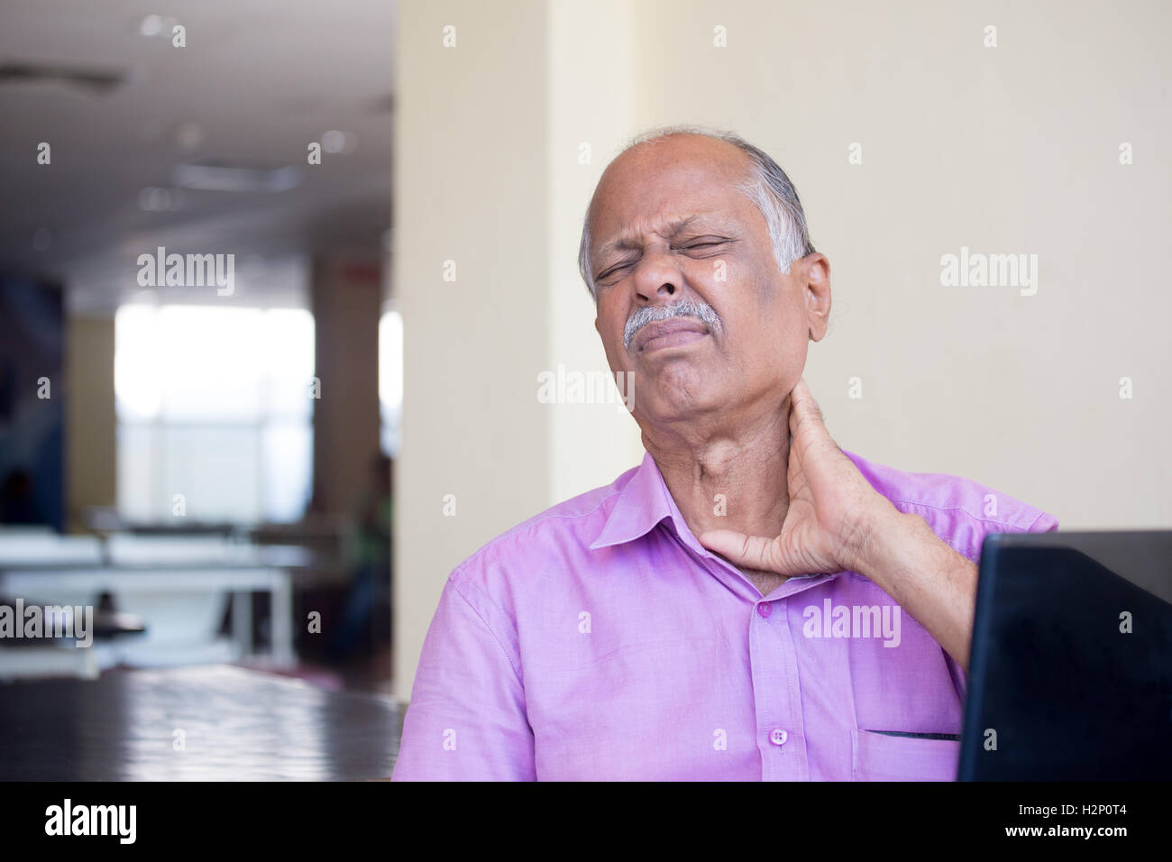 Closeup Portrait, älterer Herr in rosa t-Shirt mit Krämpfe Nackenschmerzen nach der Verwendung schwarzen Laptops ganztägig, versucht zu beruhigen Stockfoto