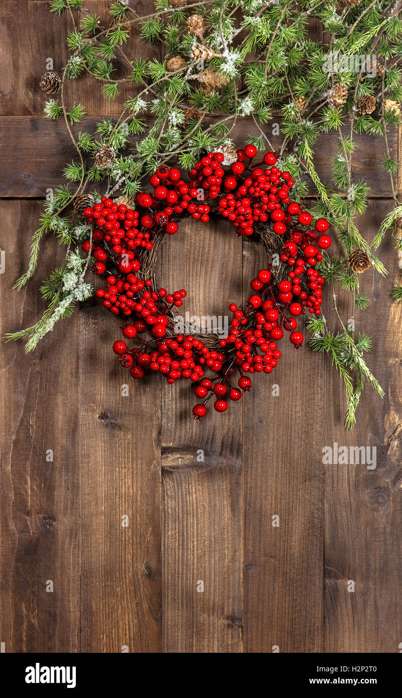 Weihnachtsbaum Äste und Kranz aus roten Beeren auf rustikalen hölzernen Hintergrund. Festliche Dekoration Stockfoto