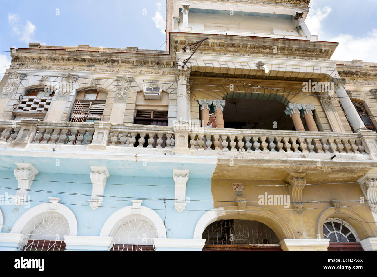 Kubanische Frau mit Lockenwickler im Haar ist aus ihrem Hause Balkon einer kolonialen Gebäude in Santiago De Cuba, Kuba lächelnd. Stockfoto