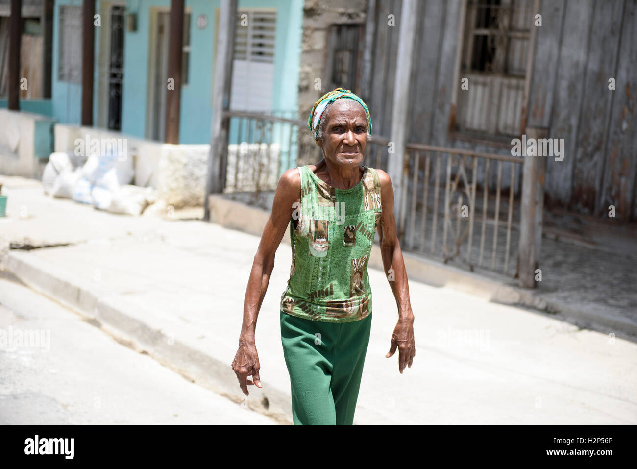 Eine ältere kubanische Frau, gekleidet in grüne Kleidung ist Fuß auf der Straße in Santiago De Cuba, Kuba. Stockfoto