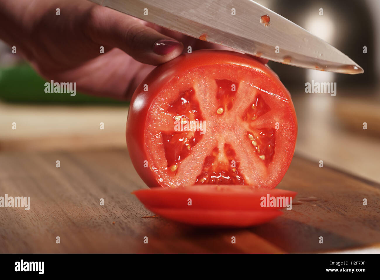 Weibliche Teenager Hand schneiden große Tomate Stockfoto