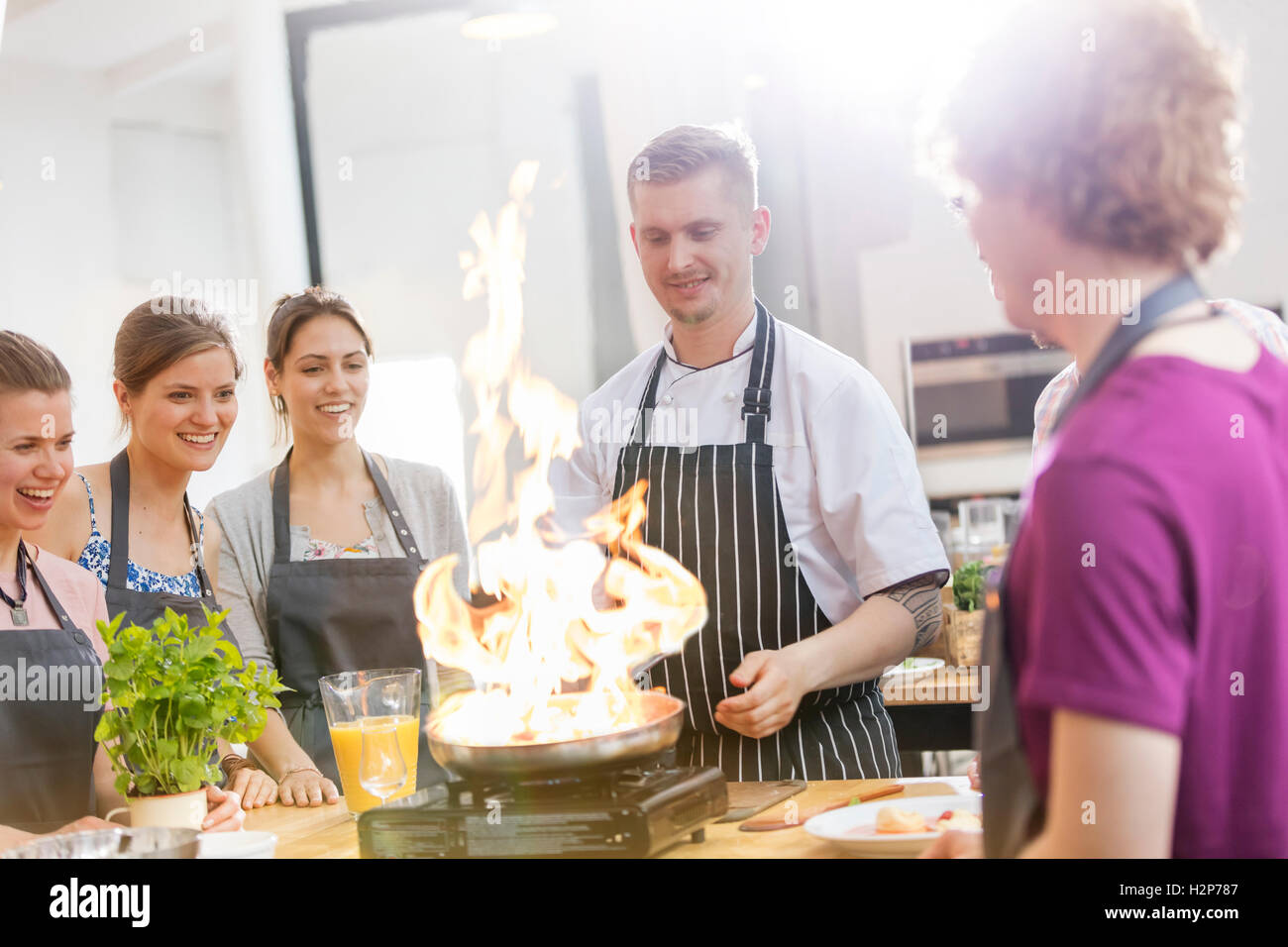 Studenten, die gerade Lehrer Flambiertem Klasse Küche kochen Stockfoto