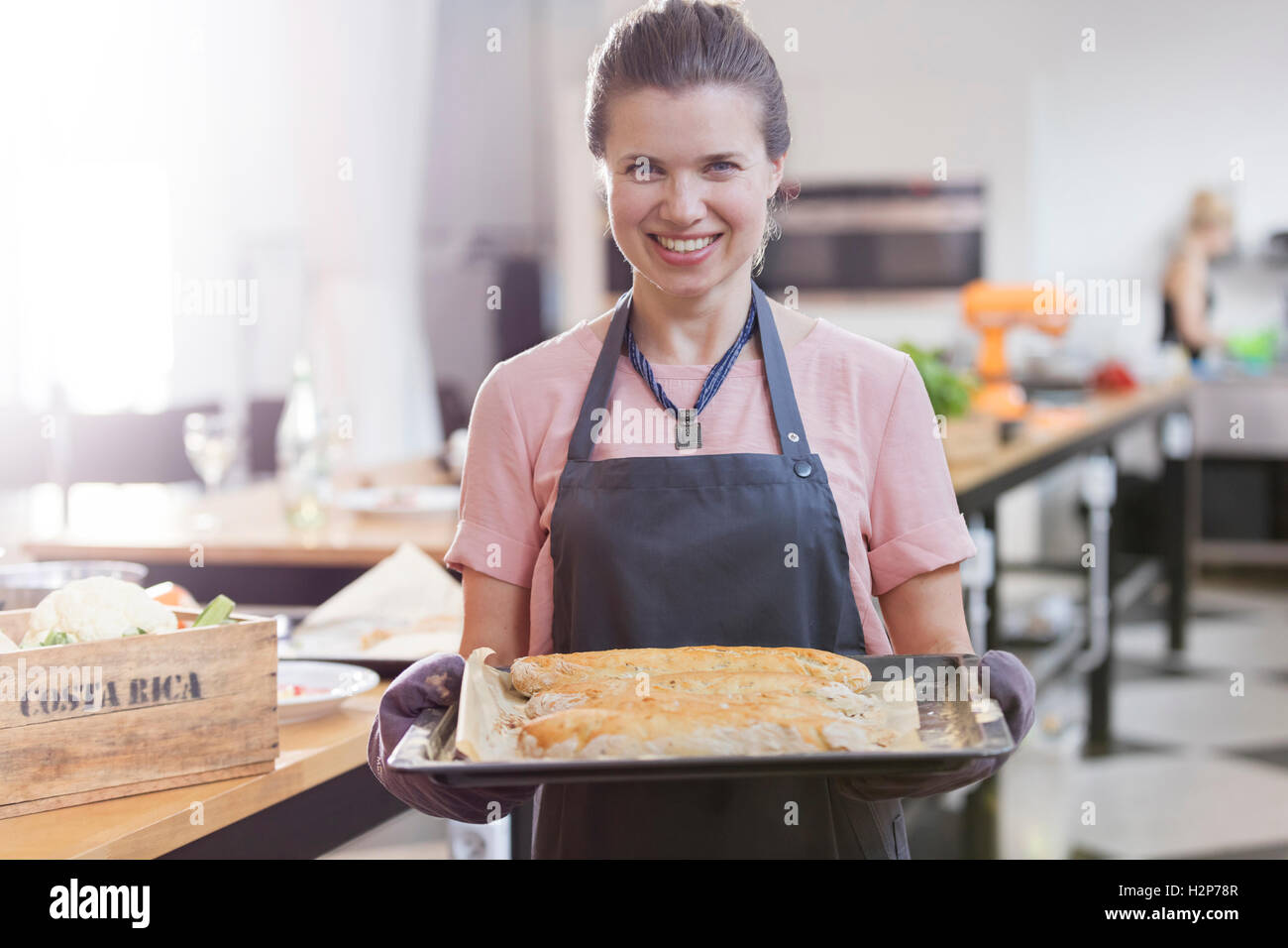 Porträt, lächelnde Frau Holding Tablett mit Essen in der Küche Klasse Küche Stockfoto