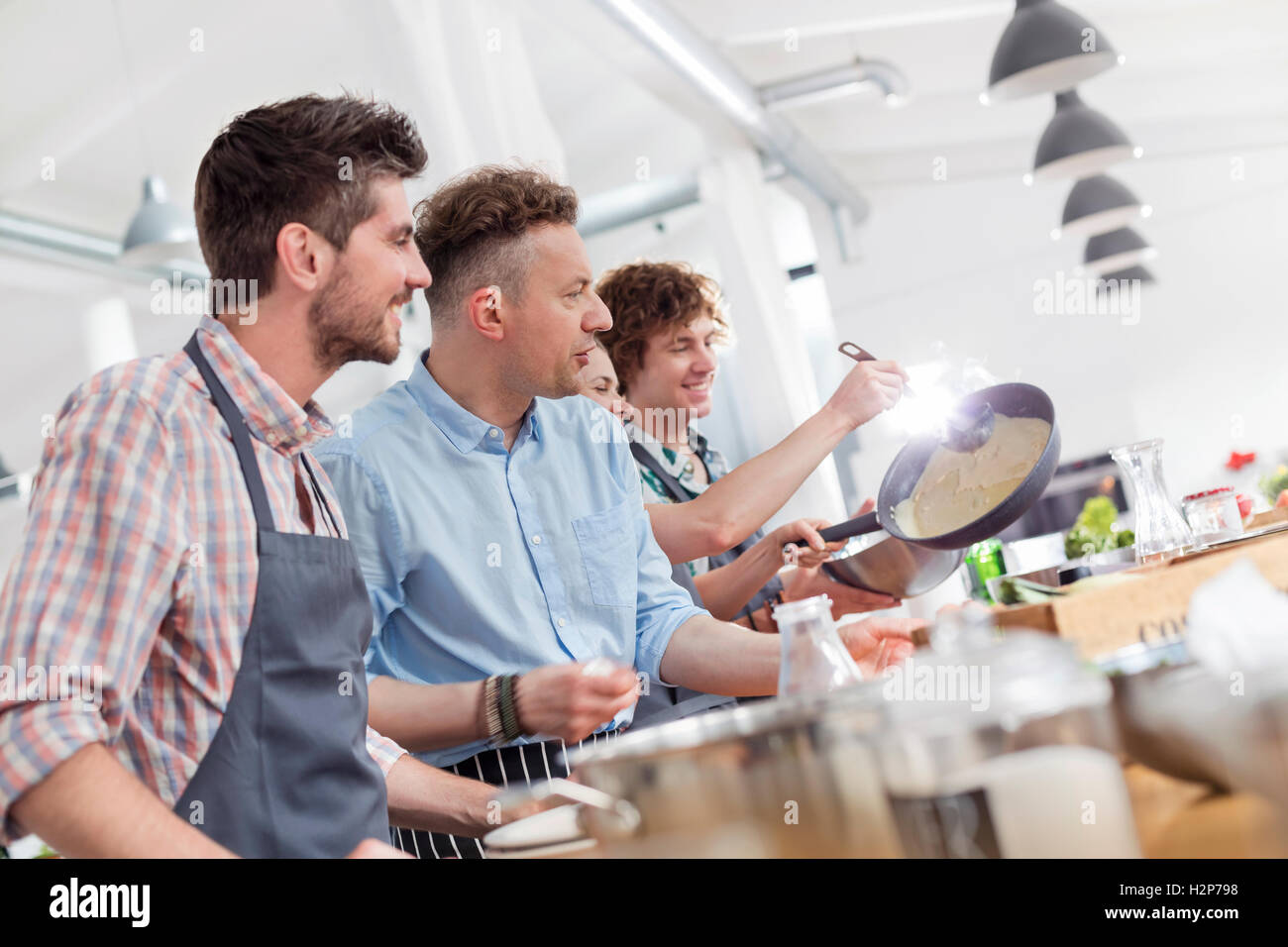 Männliche Studenten genießen Kochkurs in Küche Stockfoto