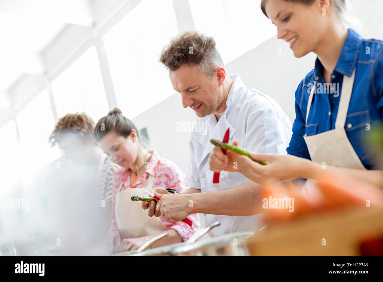 Koch-Lehrer und Schüler schälen Spargel in der Küche Klasse Küche Stockfoto
