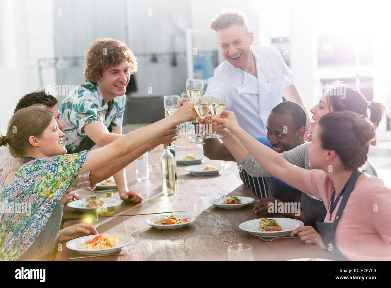 Koch-Lehrer und Schüler Toasten Weingläser in der Küche Klasse Küche Stockfoto
