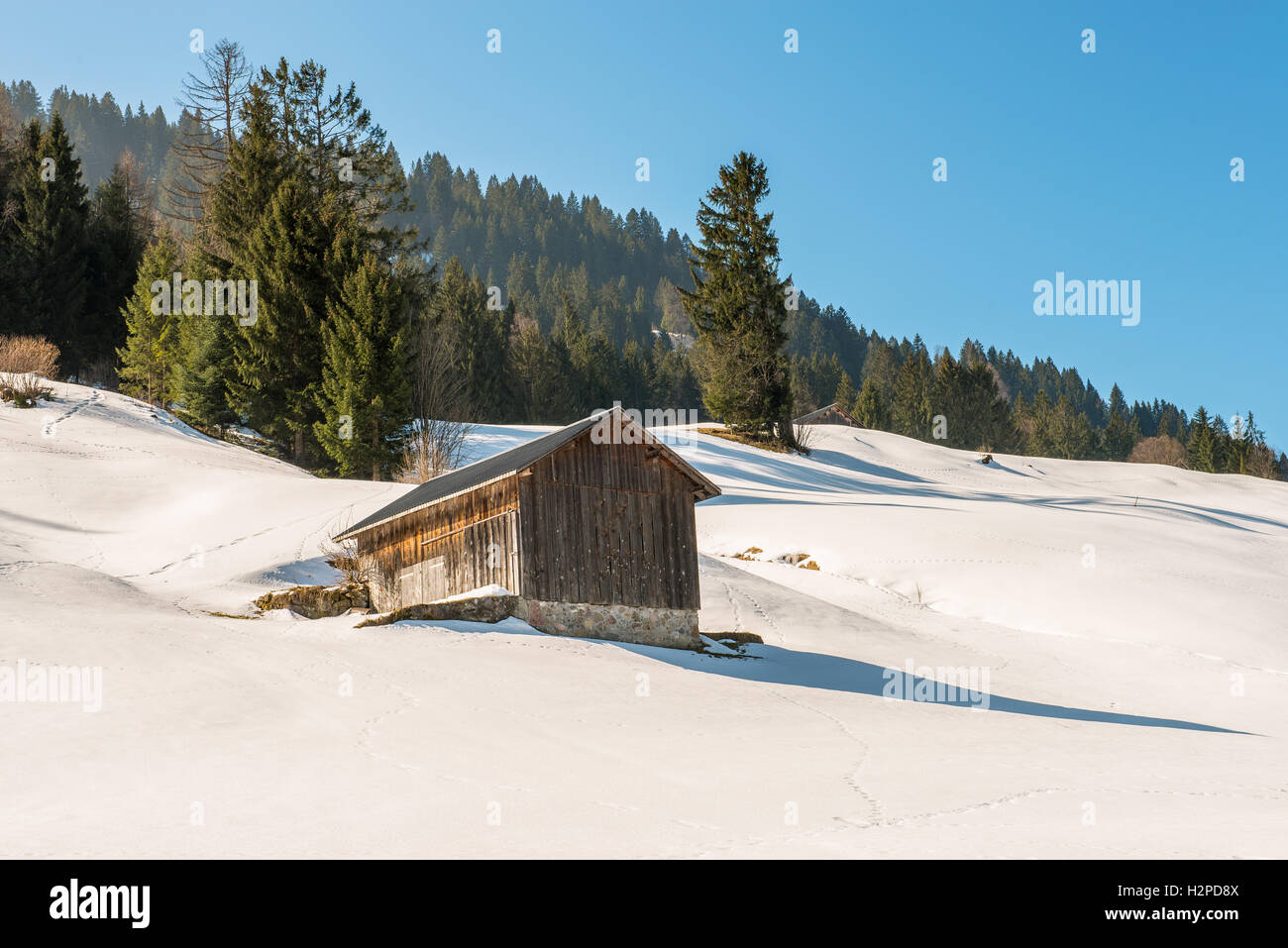 Holzhütte in alpine Winterlandschaft mit blauem Himmel Stockfoto