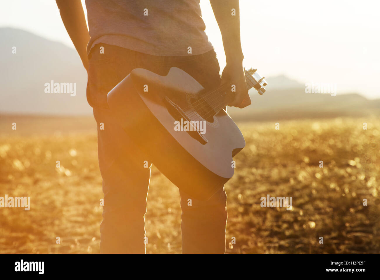 Mann mit Gitarre auf Sonnenuntergang Hintergrund Stockfoto