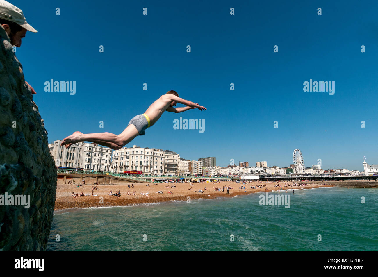 Jugendliche aus Buhnen auf Brighton Beach ins Meer springen an einem heißen Nachmittag. Stockfoto
