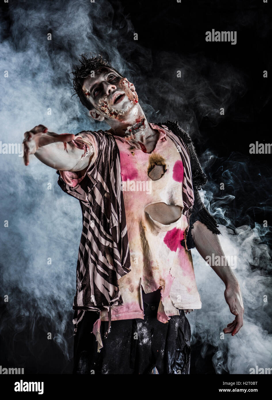 Männlichen Zombie stehen auf schwarzem Hintergrund rauchige, Hand in Richtung Kamera zu erreichen Stockfoto