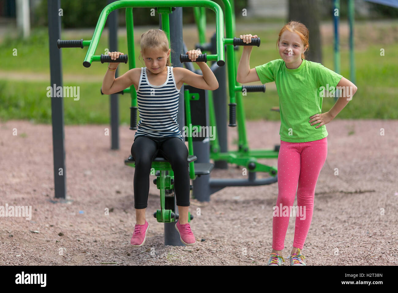 Zwei kleine süße Mädchen engagiert sich im Bereich Fitnessgeräte im Freien. Stockfoto