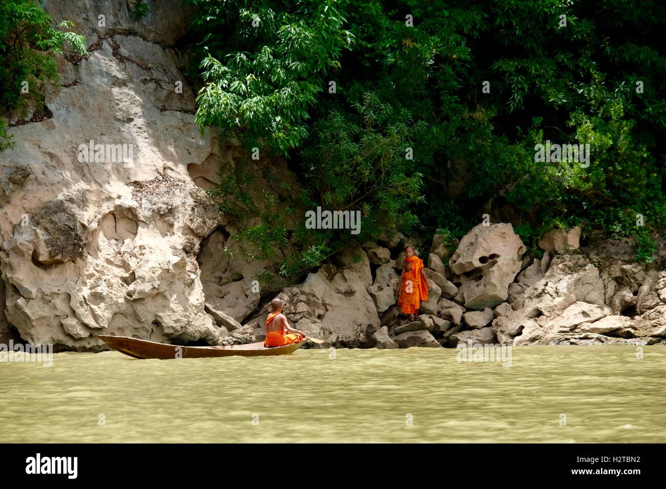 2 junge Mönche unter hölzernen Kanu Nam Fluss in Laos Stockfoto