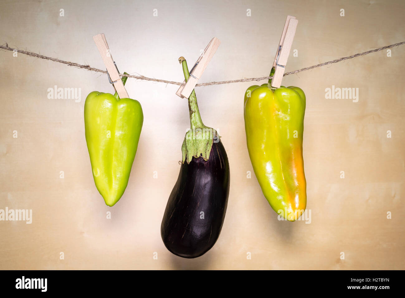 Auberginen und Paprika auf hölzernen Hintergrund hängen an einem Seil Stockfoto