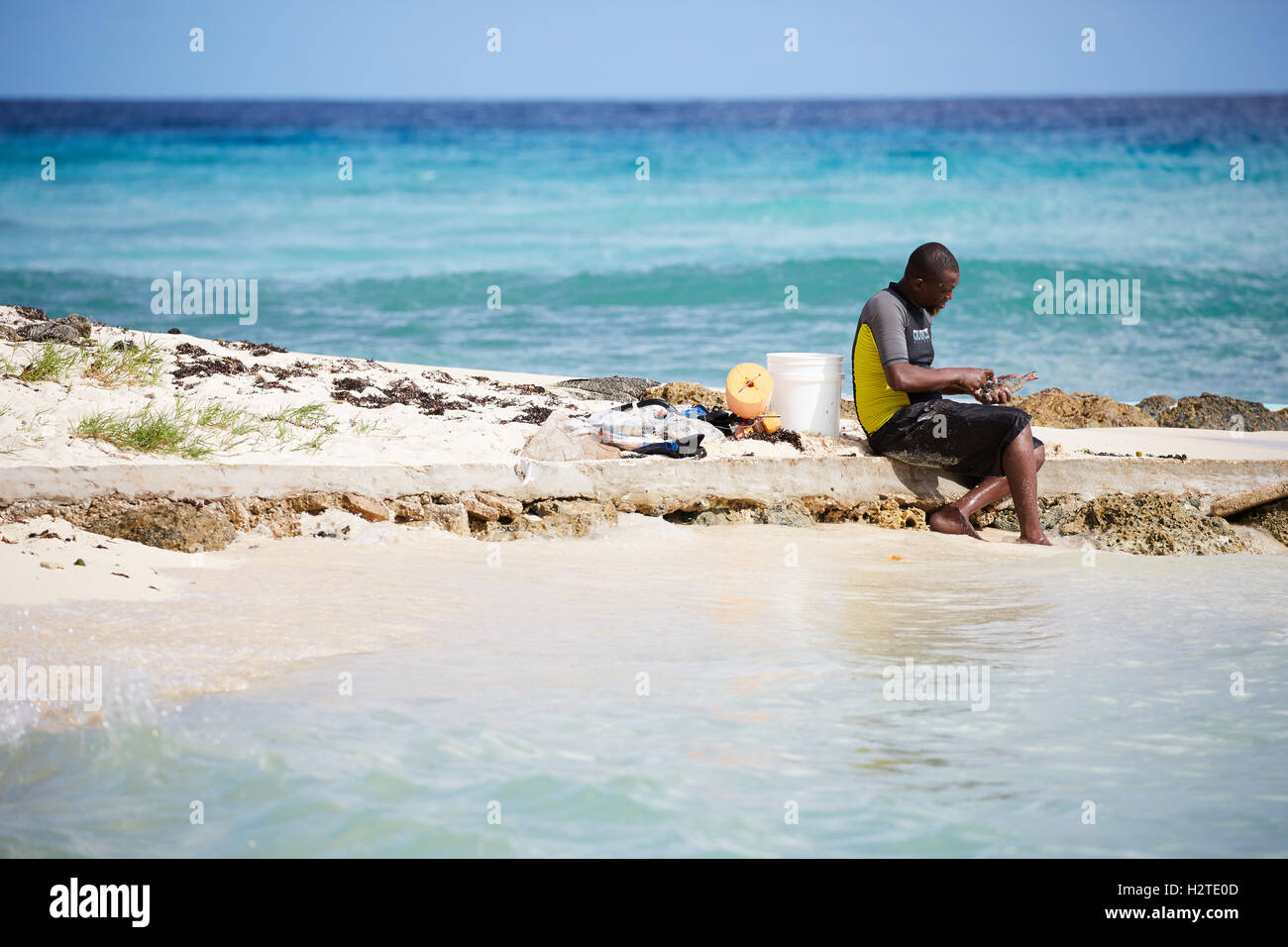 Barbados Hastings Bay Fischer schwarzen männlichen jungen einheimischen Fischen am Strand Meer Armen heruntergekommenen Müll ungepflegt beraubt comm Stockfoto