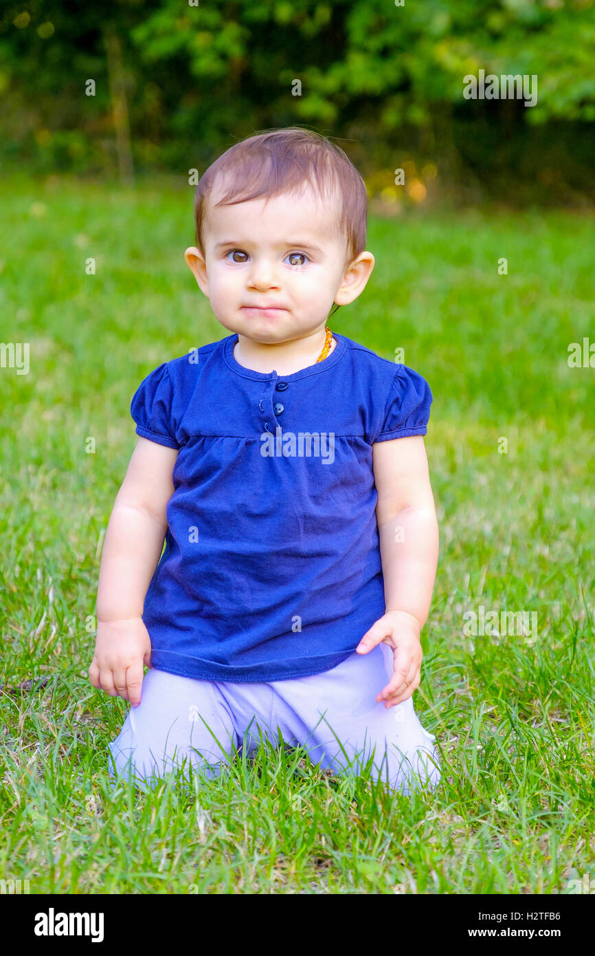verwirrt Baby auf Knien Rasen Stockfoto