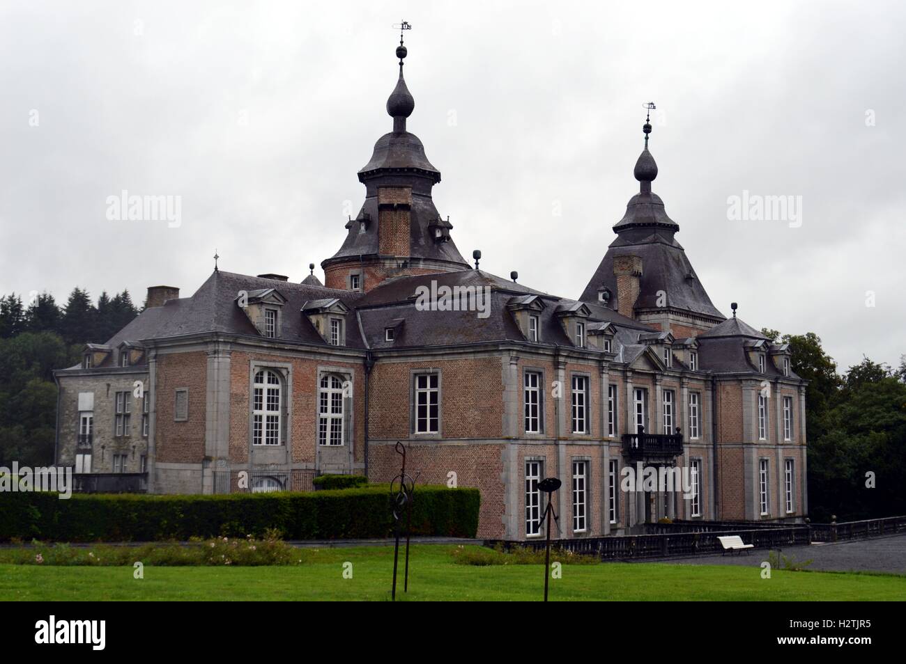 Ehemalige Burg im Wald mit einem Weg von Bäumen und eine große Liegewiese. Stockfoto