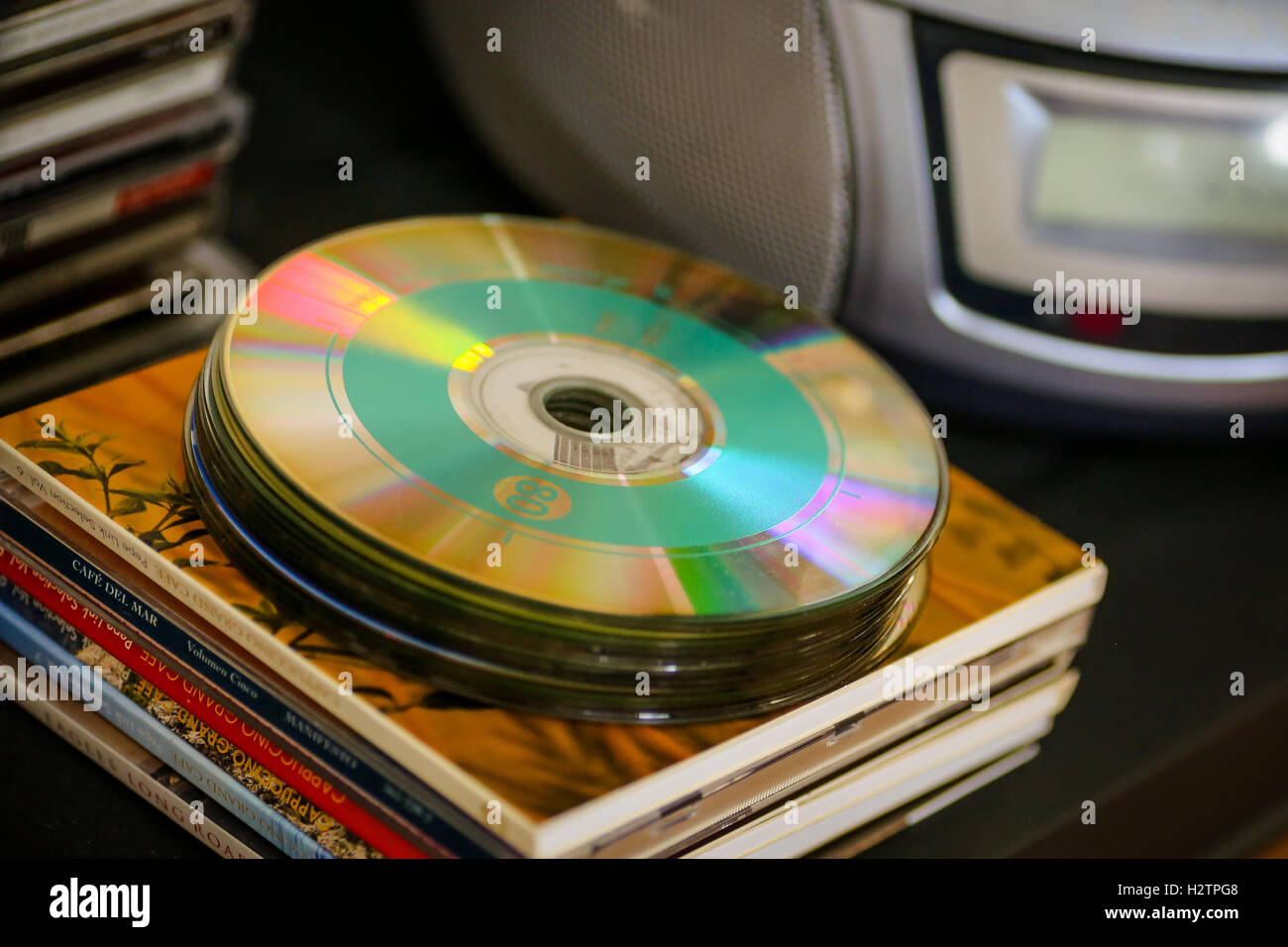 Ein Stapel von Musik-CDs auf vielen CD-Hüllen mit Radio und CD-Player im Hintergrund Stockfoto