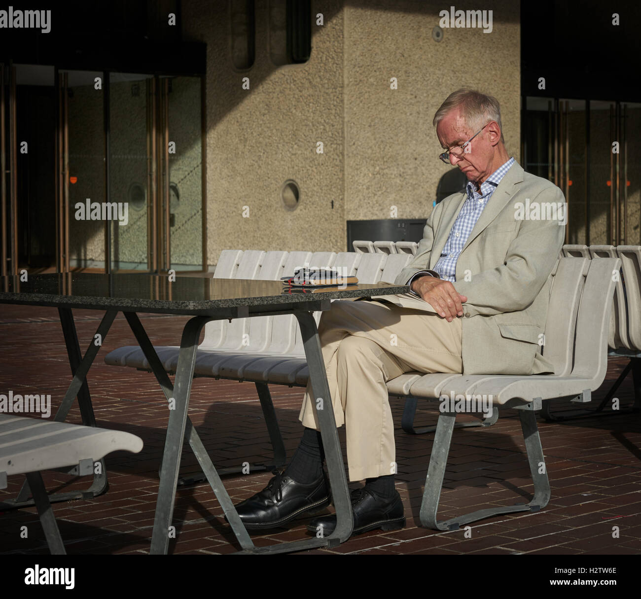 Mann sitzt in der Sonne.  Alter Mann lesen.  schlafen in der Sonne.  weißen Anzug. Stockfoto