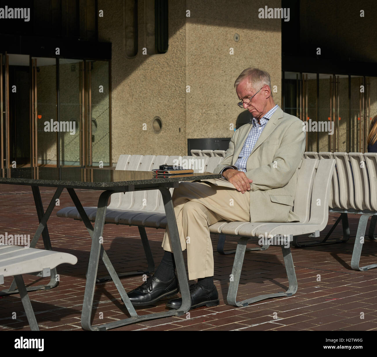 Mann sitzt in der Sonne.  Alter Mann lesen.  schlafen in der Sonne.  weißen Anzug. Stockfoto