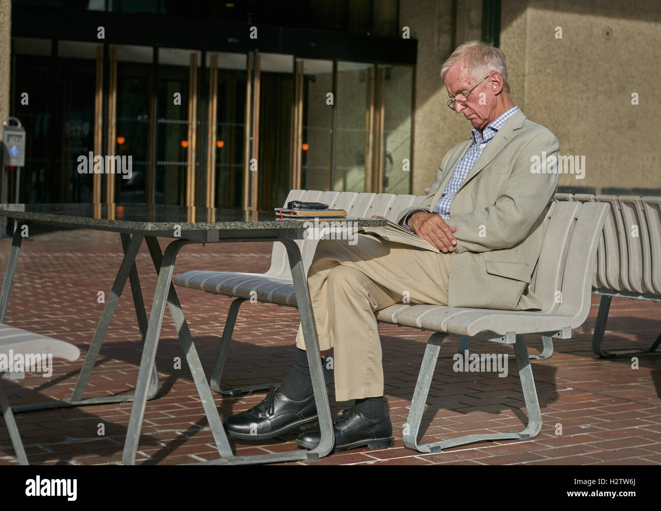 Mann sitzt in der Sonne.  Alter Mann lesen.  schlafen in der Sonne.  weißen Anzug. Stockfoto