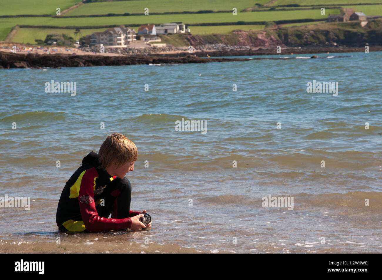 Junge im Neoprenanzug Aufnahmen von Wellen mit kleinen Action-Kamera Stockfoto