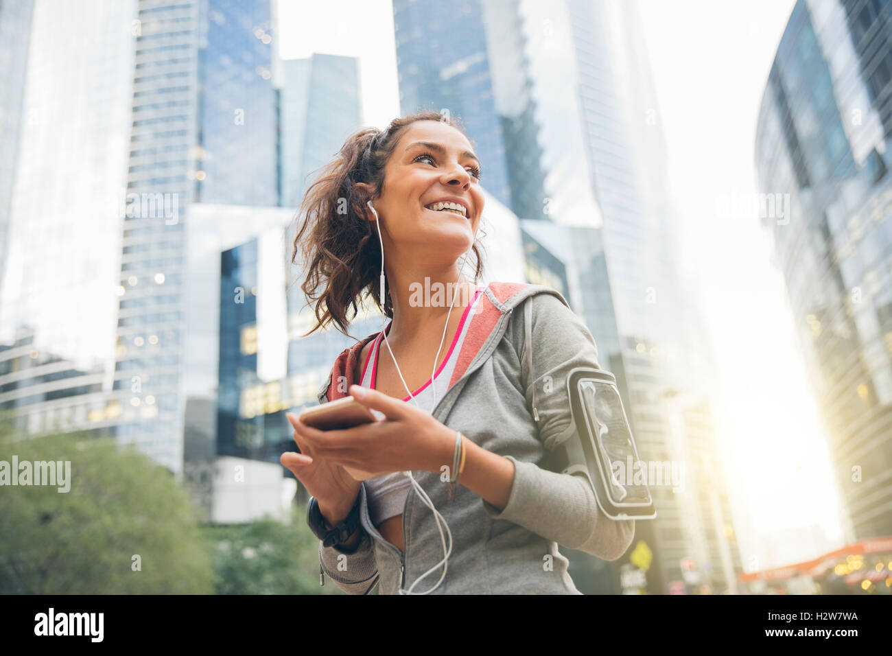 Junge Frau Läufer Armbinde tragen und anhören von Musik über Kopfhörer Stockfoto