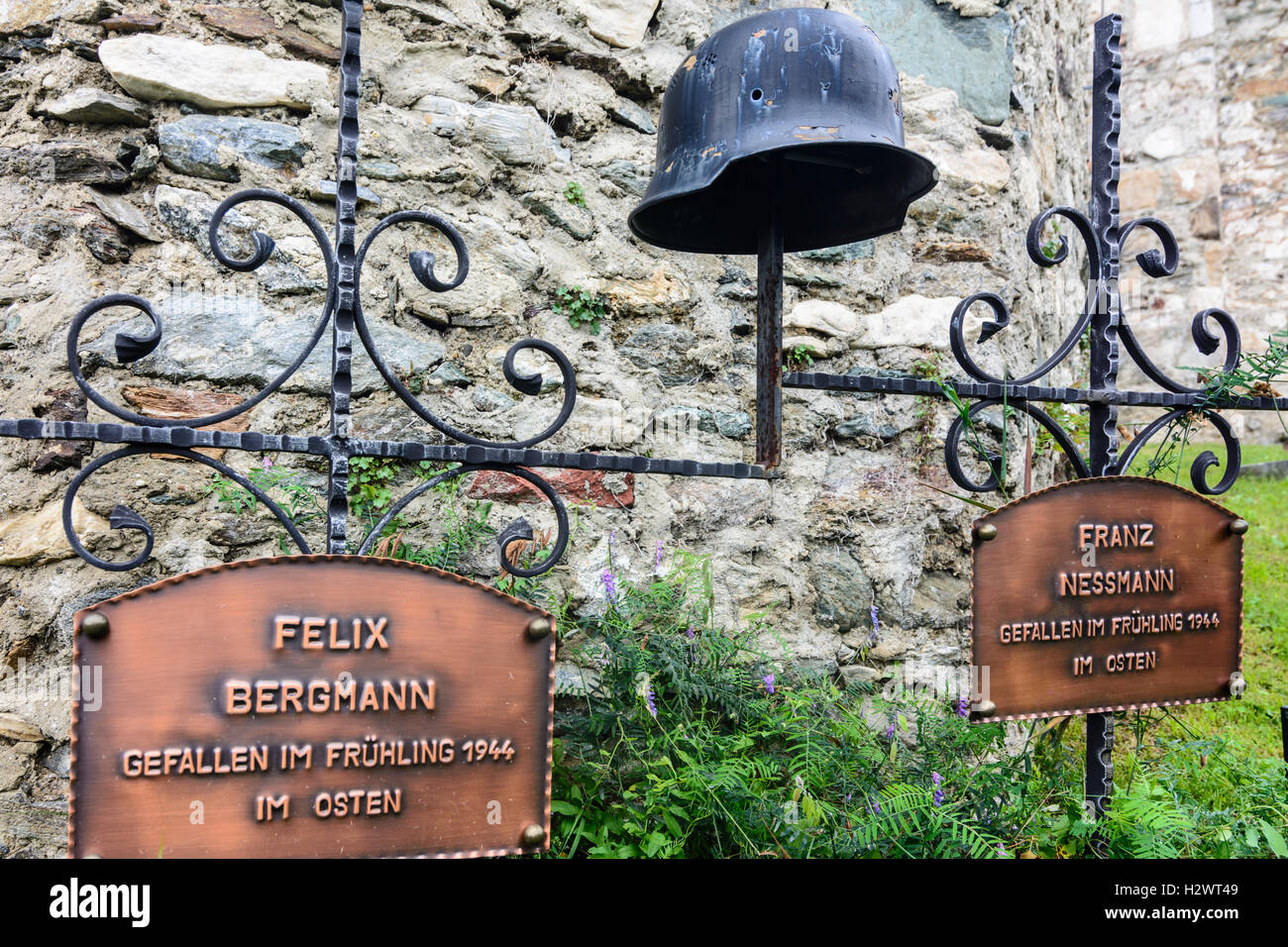 Maria Saal: schwere Kreuze für Soldaten gestorben 2. Weltkrieg an der Ostfront, Bekämpfung Helm mit Einschussloch an der Kirchenmauer in Ka Stockfoto