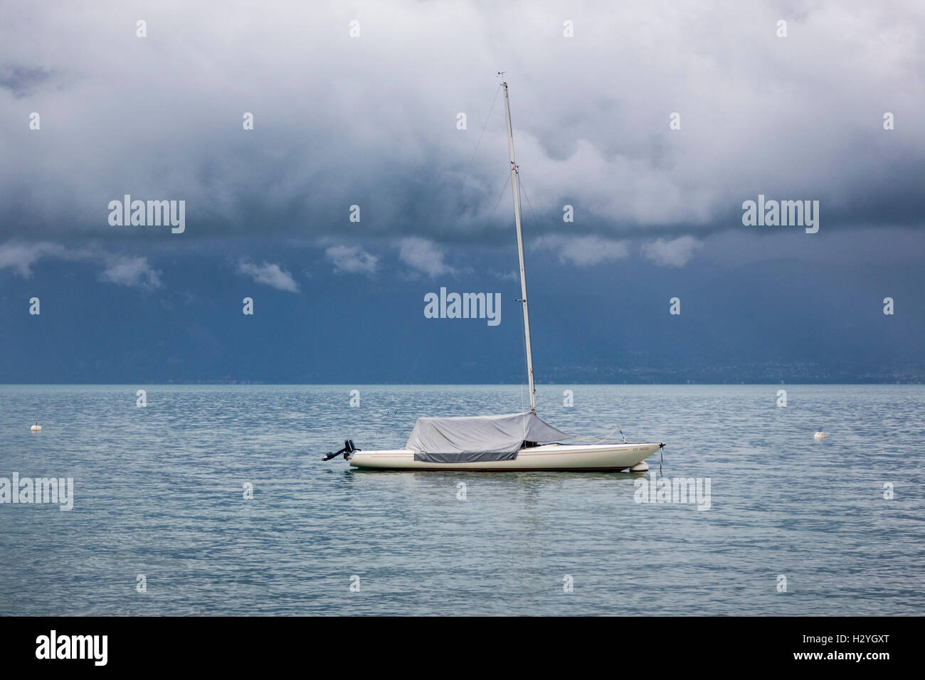 Einsamer Yacht unter niedrigen rollenden Gewitterwolken über dem Genfer See, Schweiz Stockfoto