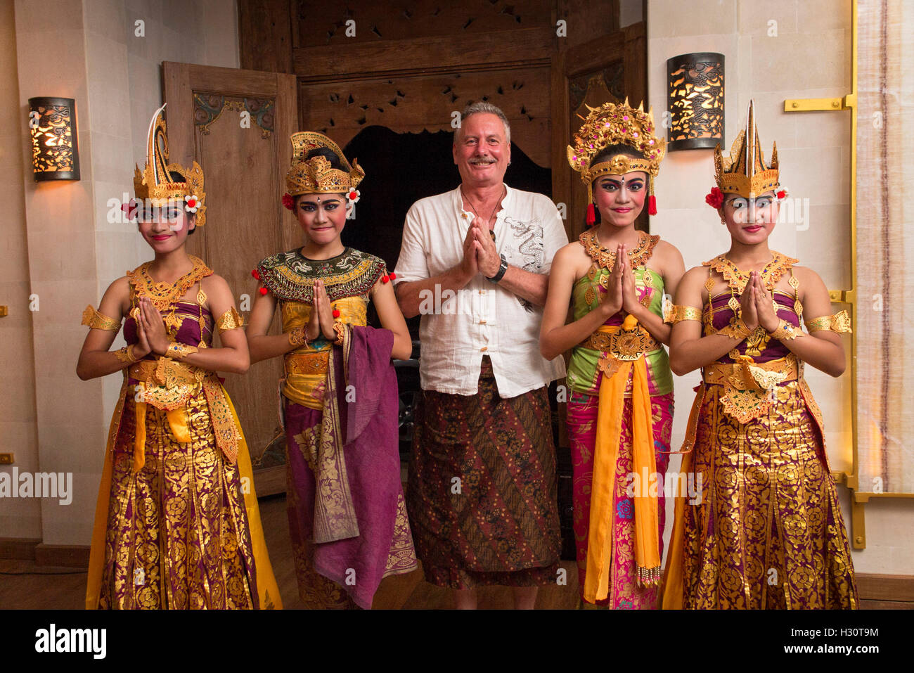 Indonesien, Bali, Amed, Gruppe von jungen balinesische Tänzerinnen mit älteren westlichen Touristen tragen sarong Stockfoto