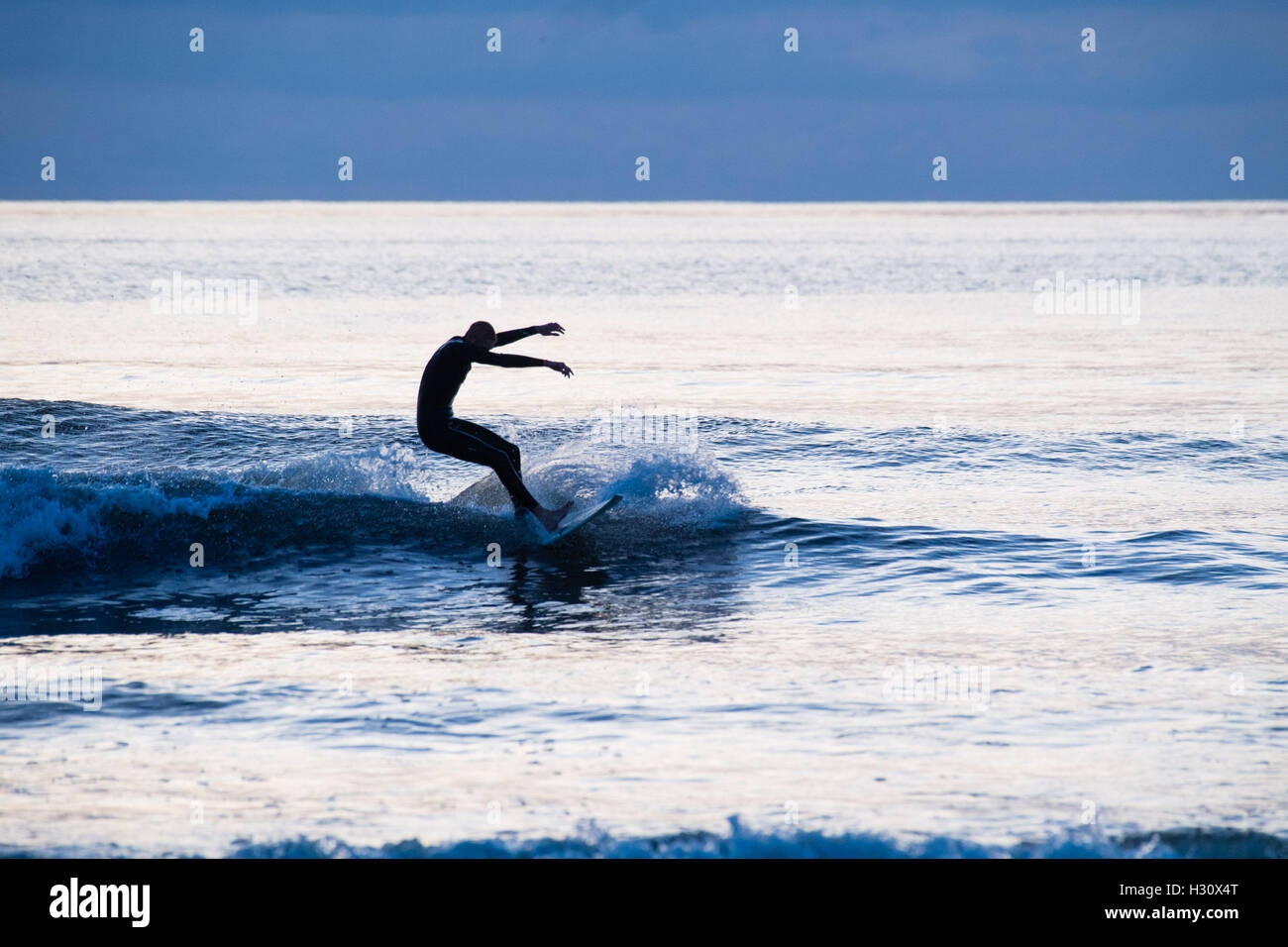 Aberystwyth Wales UK, Sonntag, 2. Oktober 2016 UK Wetter: am Ende eines Tages fast ohne Unterbrechung blauer Himmel und helle warme Herbstsonne, Surfer genießen Sie die Wellen auf dem Meer in der Abenddämmerung in Aberystwyth, Wales.   Das Wetter für die nächsten Tage wird voraussichtlich gut trocken und ständiger Foto Credit: Keith Morris / Alamy Live News Stockfoto
