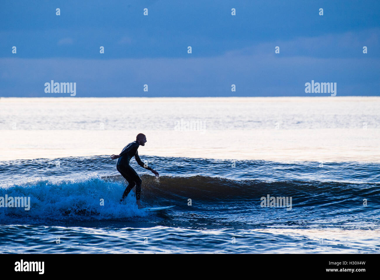 Aberystwyth Wales UK, Sonntag, 2. Oktober 2016 UK Wetter: am Ende eines Tages fast ohne Unterbrechung blauer Himmel und helle warme Herbstsonne, Surfer genießen Sie die Wellen auf dem Meer in der Abenddämmerung in Aberystwyth, Wales.   Das Wetter für die nächsten Tage wird voraussichtlich gut trocken und ständiger Foto Credit: Keith Morris / Alamy Live News Stockfoto