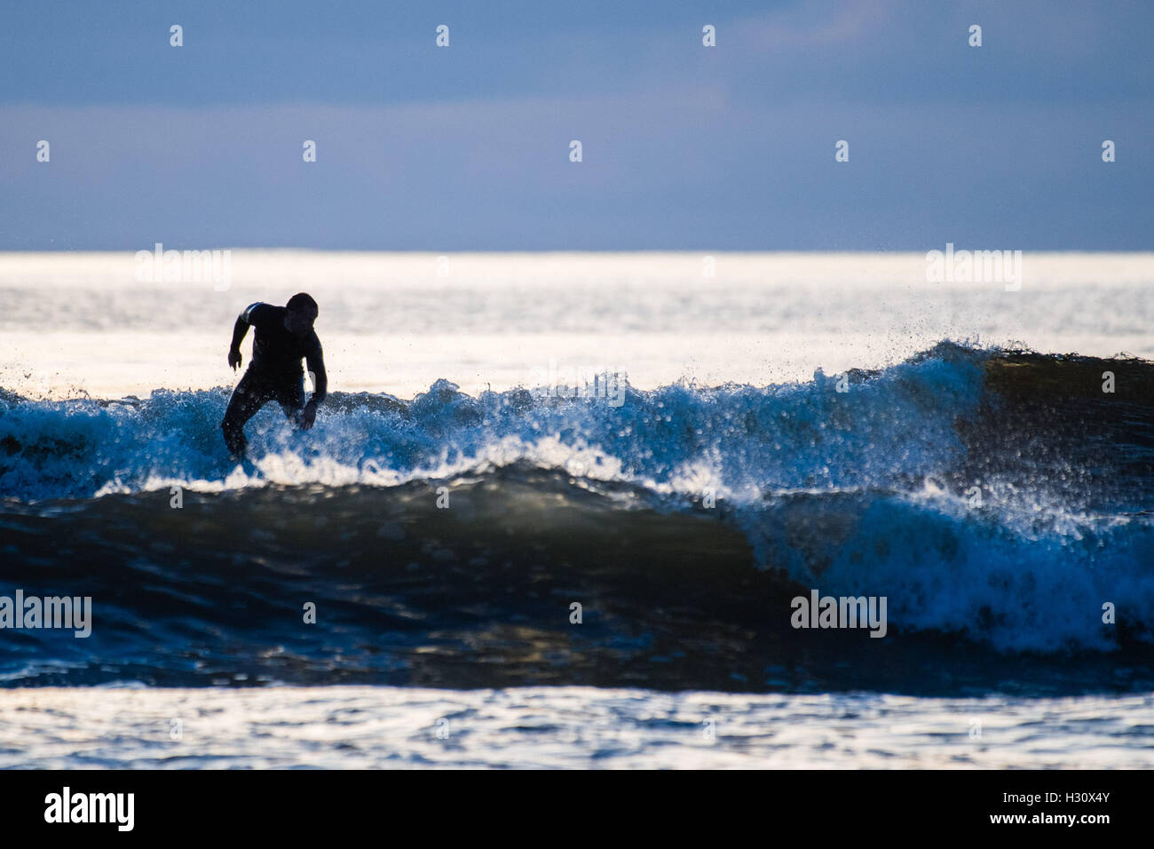 Aberystwyth Wales UK, Sonntag, 2. Oktober 2016 UK Wetter: am Ende eines Tages fast ohne Unterbrechung blauer Himmel und helle warme Herbstsonne, Surfer genießen Sie die Wellen auf dem Meer in der Abenddämmerung in Aberystwyth, Wales.   Das Wetter für die nächsten Tage wird voraussichtlich gut trocken und ständiger Foto Credit: Keith Morris / Alamy Live News Stockfoto