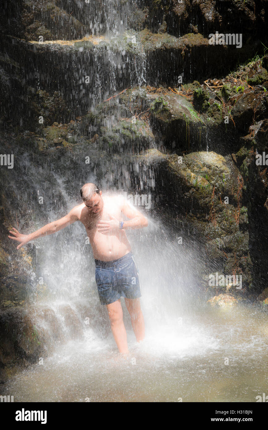 Mann unter einem Wasserfall Stockfoto