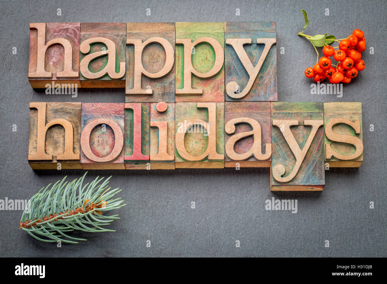 Happy Holidays-Banner oder Grußkarte im Buchdruck Holzart Blöcke gegen Schiefer Stockfoto