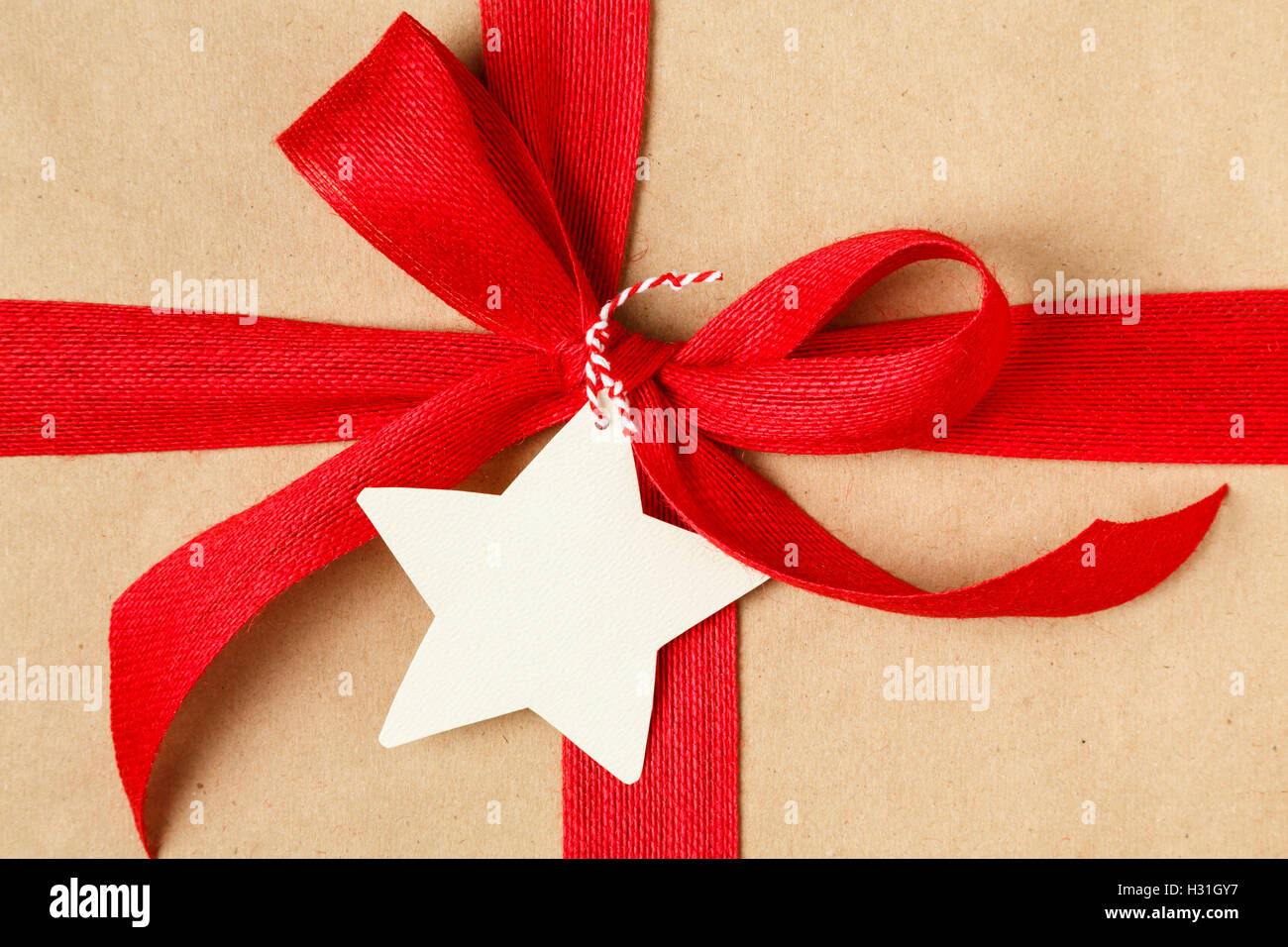 Weihnachtsgeschenk mit roter Schleife und leere Geschenkanhänger. Einfaches Recycling Geschenkpapier und natürliche Jute-Band. Stockfoto