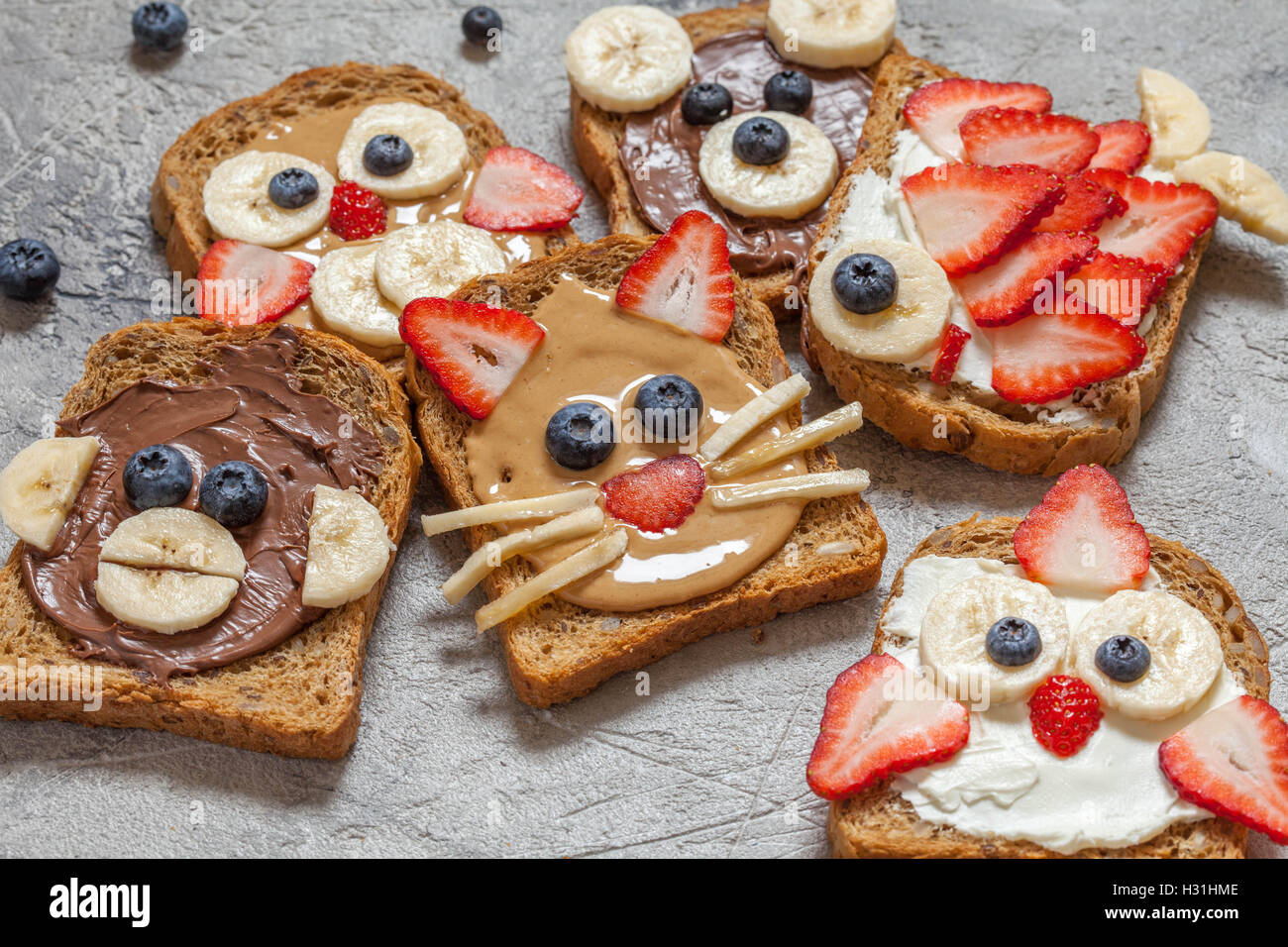 Lustige Tier Gesichter Toast mit Spreads, Banane, Erdbeere und Heidelbeere Stockfoto
