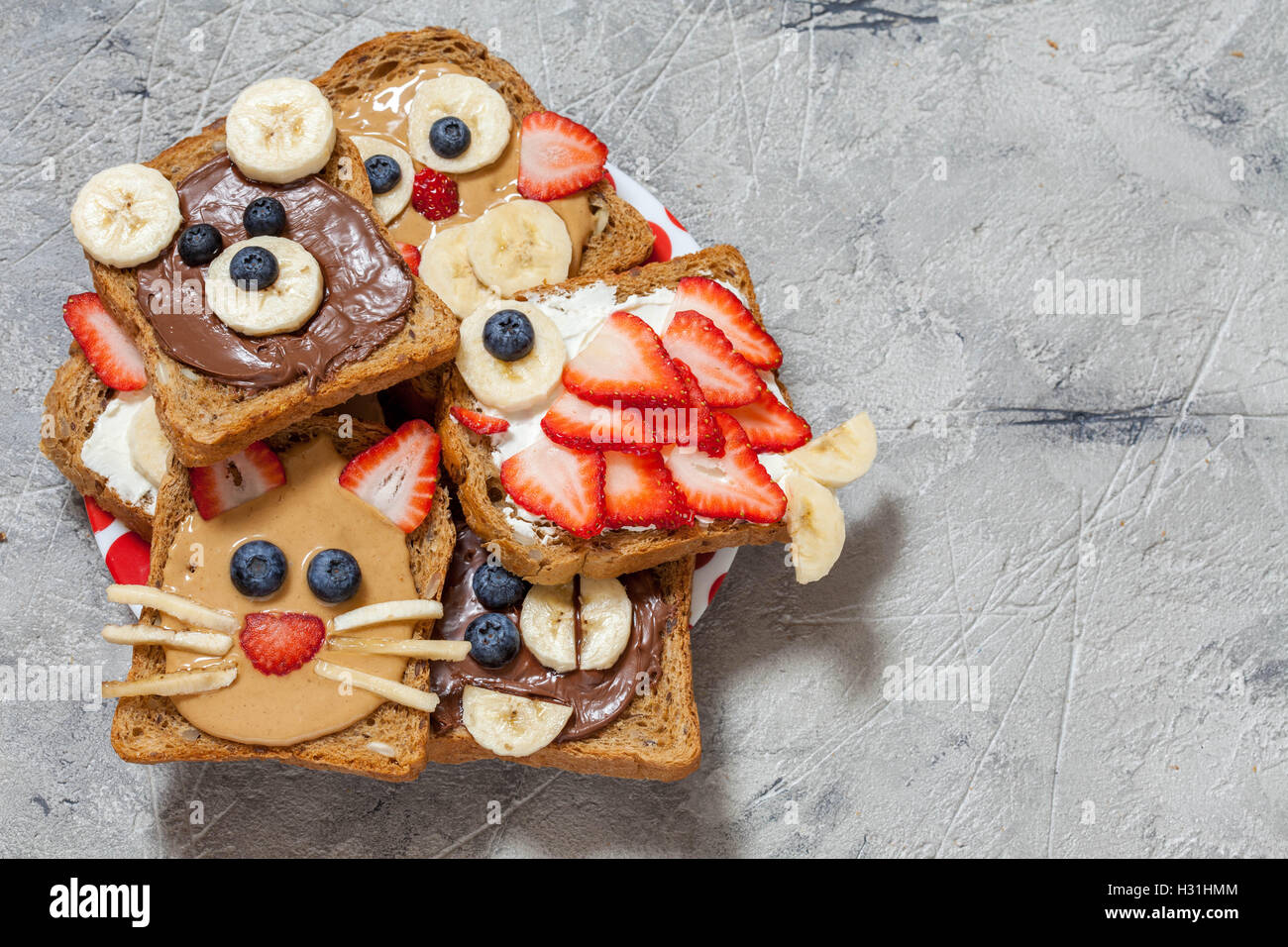 Lustige Tier Gesichter Toast mit Spreads, Banane, Erdbeere und Heidelbeere Stockfoto