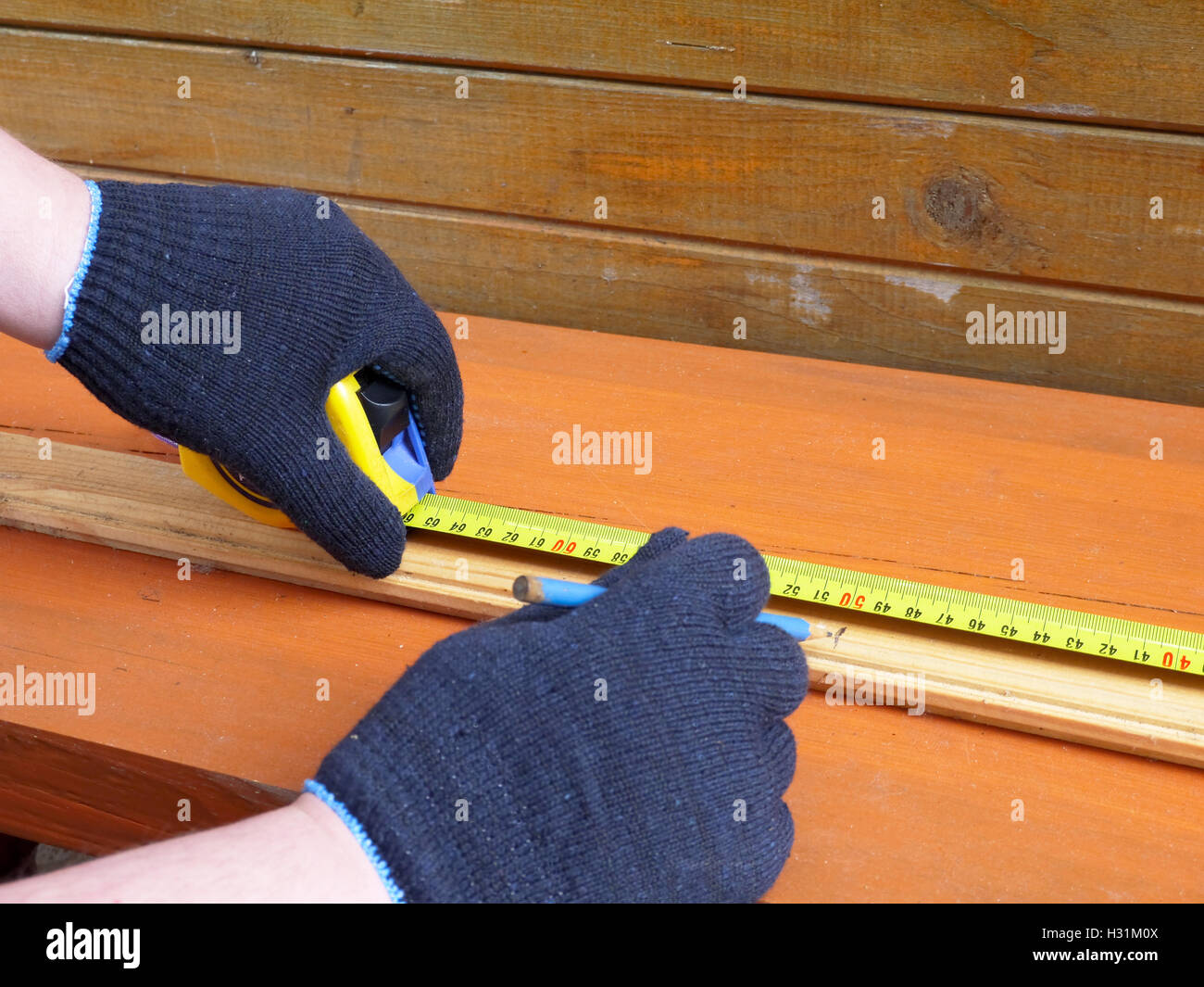 Mann in blaue Handschuhe Maßnahmen Holzbrett Stockfoto