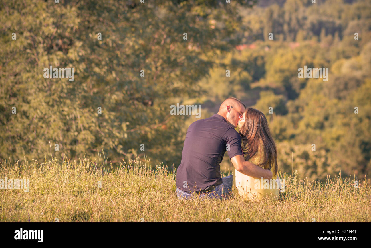 junges Paar zurück Rückansicht im freien küssen sonnigen Wald Gebirge Stockfoto