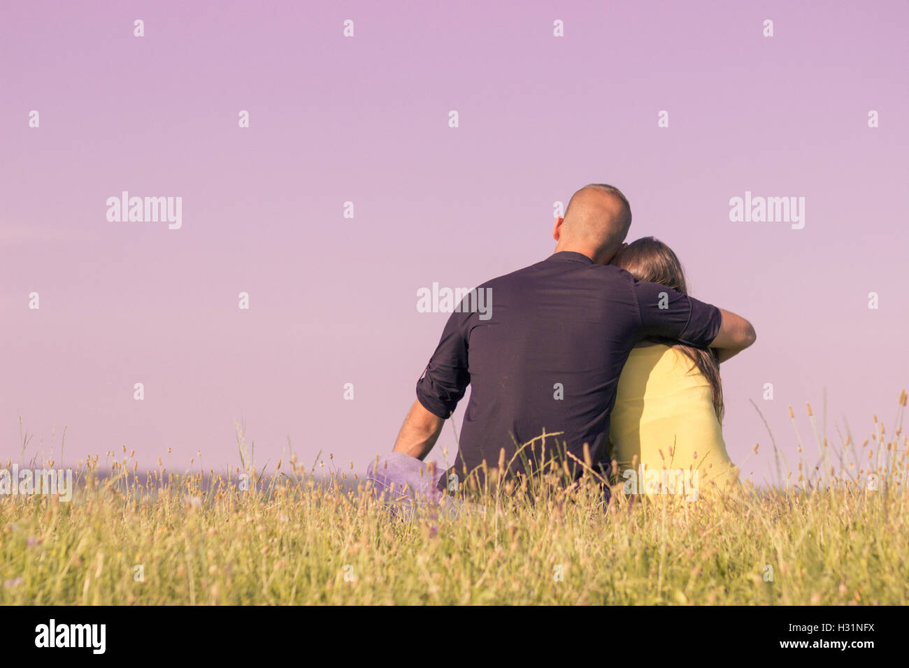 junges Paar 20er Jahre umarmt zurück Rückansicht Himmel lila Stockfoto