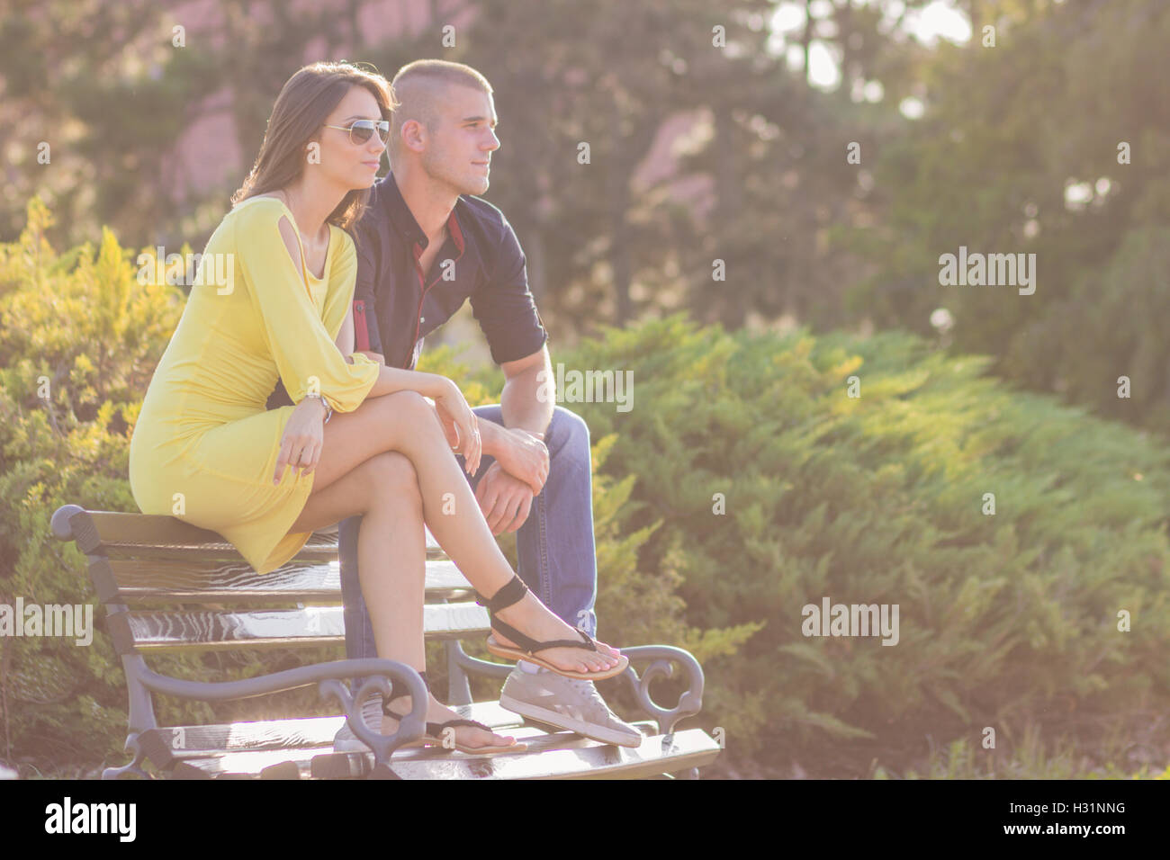 junges Paar sitzt auf einer Bank sonnigen Tag im freien Stockfoto