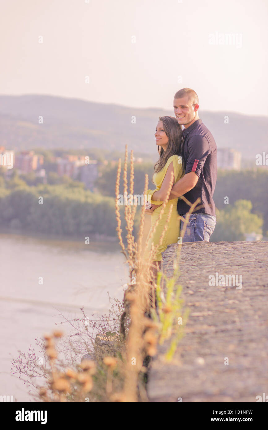 junges Paar stehen auf Felsen hoch über sonnigen Tag umarmt Stockfoto