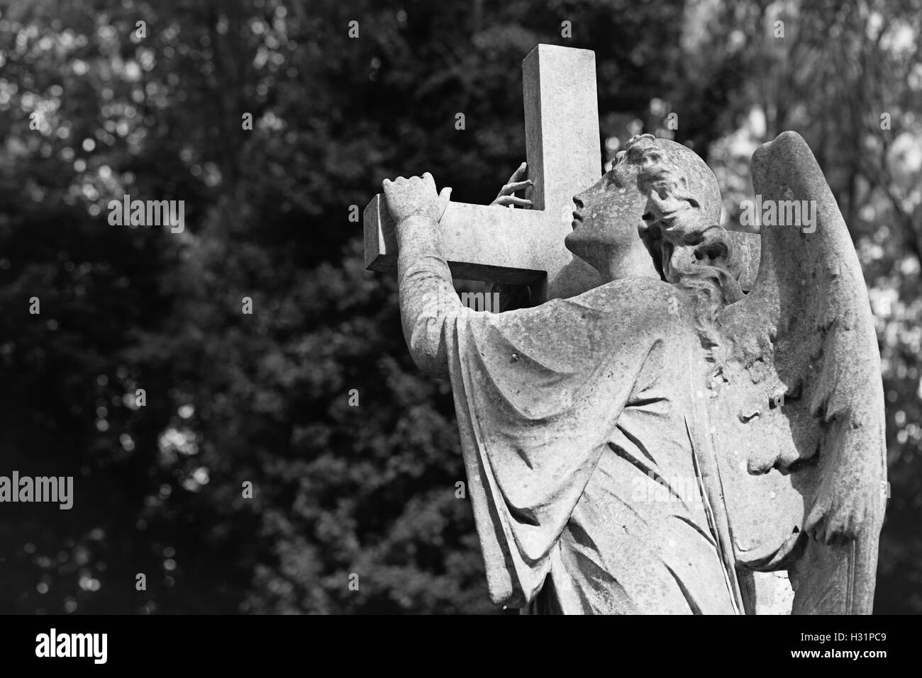 Statue eines Engels tragen einen Kreuz Grabstein Grabstein auf Highgate Cemetery East in London, England. Stockfoto