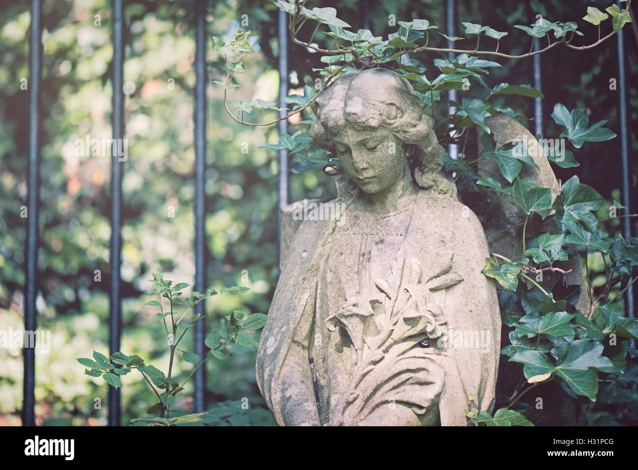 Tombstone Grabstein Statue von Frau Engel mit Lilien Blumen bedeckt Rebe auf Highgate Cemetery East in London, England. Stockfoto