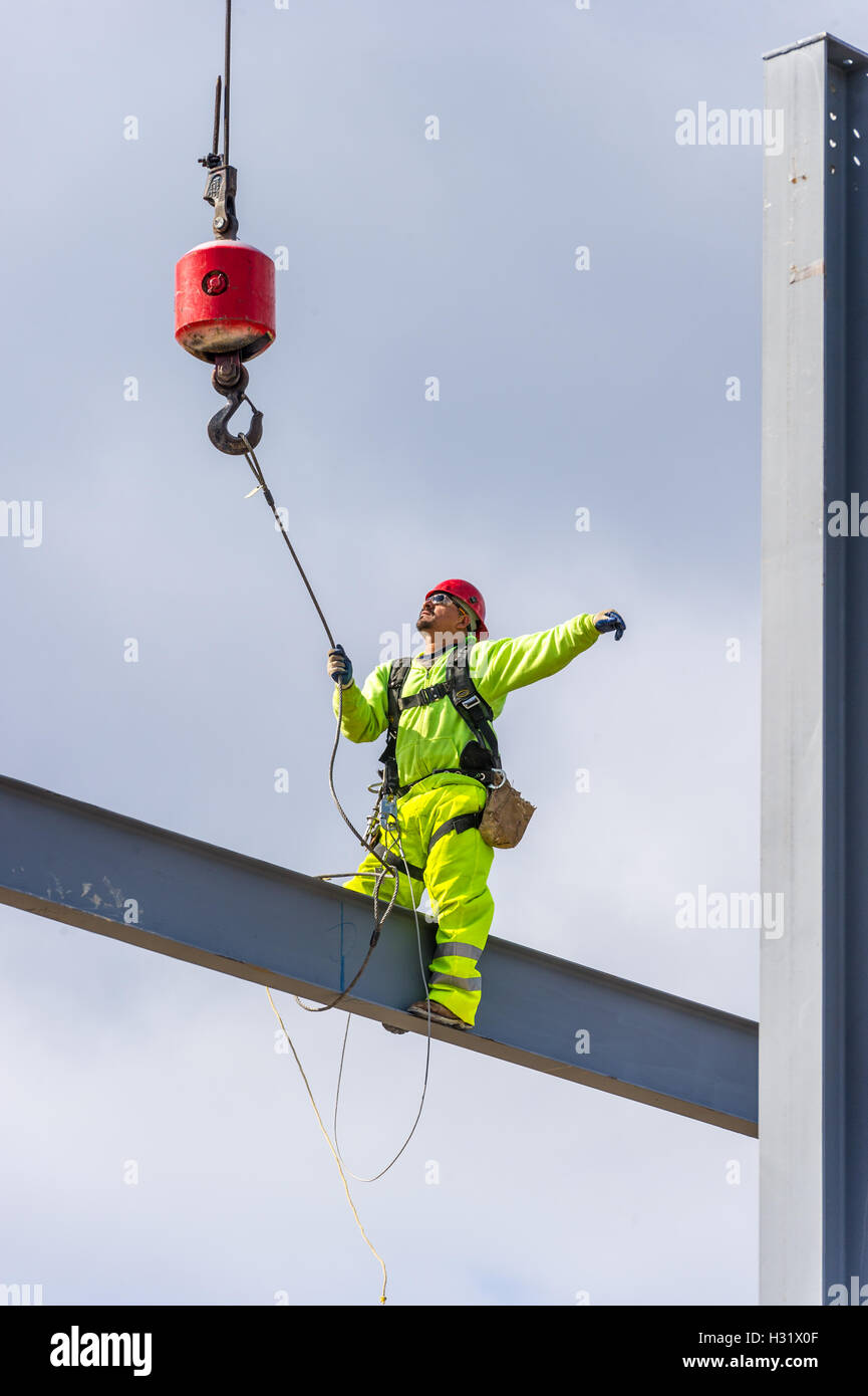 Eiserner Arbeiter sitzt auf einem Balken auf einer Baustelle Stockfoto