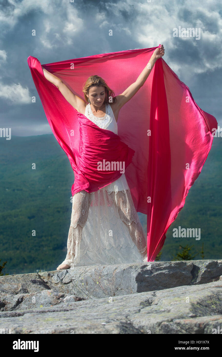 Tänzerin im weißen Kleid wehenden roten Stoff im Wind am Gipfel des Mt. Kearsarge, NH. Stockfoto