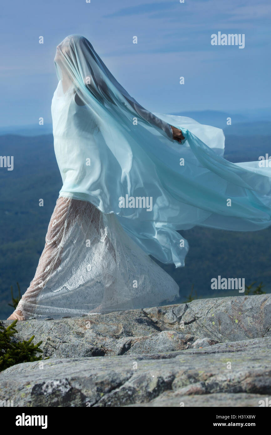 Tänzerin in weißes Kleid gehüllt in grünem Stoff im Wind am Gipfel des Mt. Kearsarge, New Hampshire. Stockfoto