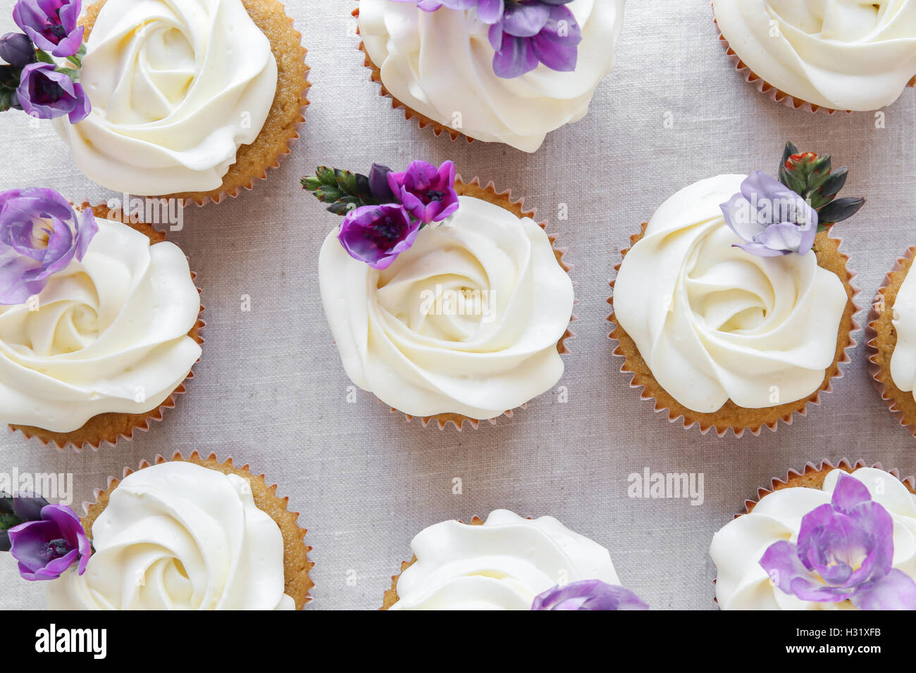 Rose Blume Zuckerguss Vanille Cupcakes mit lila essbare Blumen Stockfoto